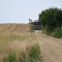 Ciężki sprzęt wykonuje prace poscaleniowe na drodze do p&oacute;l w Chodowie